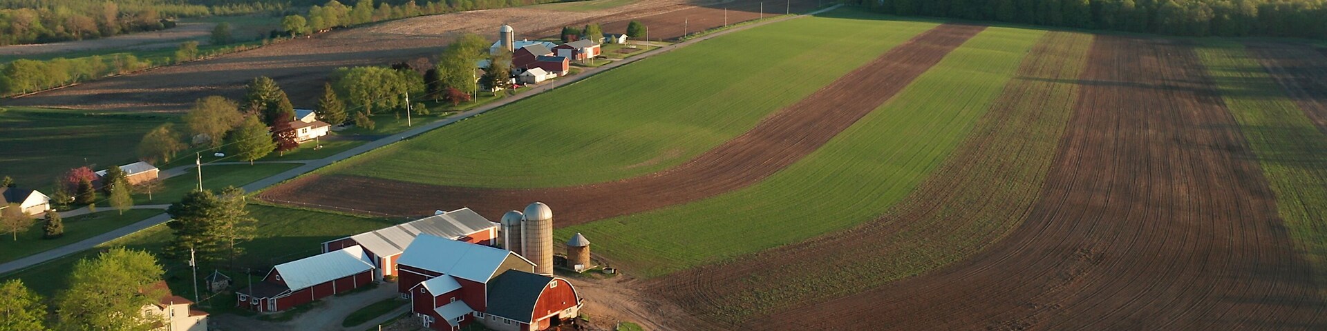 Vista aérea de uma paisagem rural com campos, celeiros e um silo.
