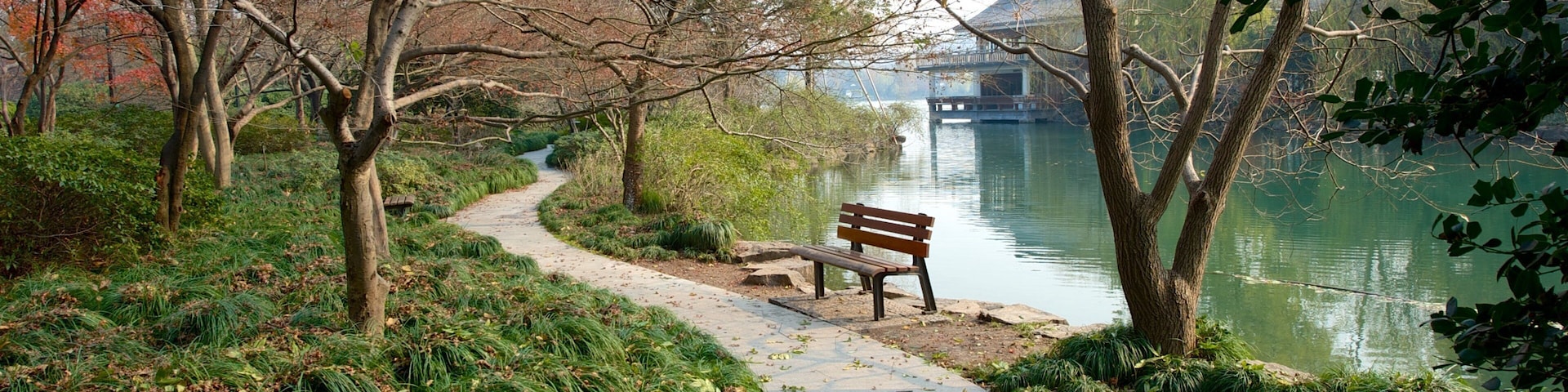 A park with a walking path, a bench, and a body of water.