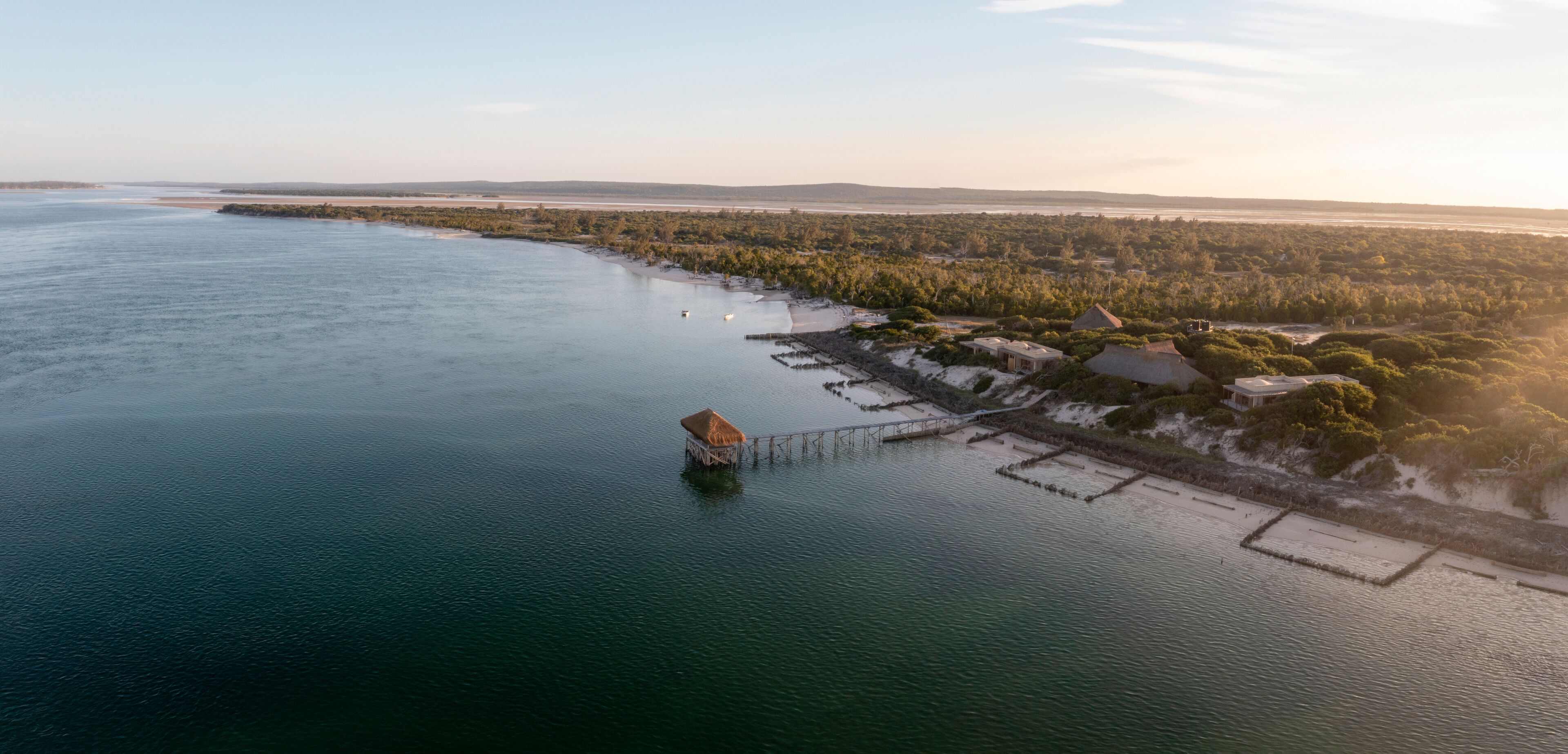 Aerial view of Thatched Pier, ocean, coastline, forest, houses, Ilha Lunene, Inhambane Province, Mozambique.