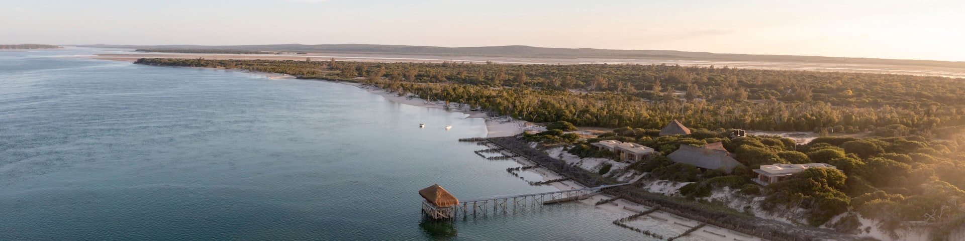 Aerial view of Thatched Pier, ocean, coastline, forest, houses, Ilha Lunene, Inhambane Province, Mozambique.