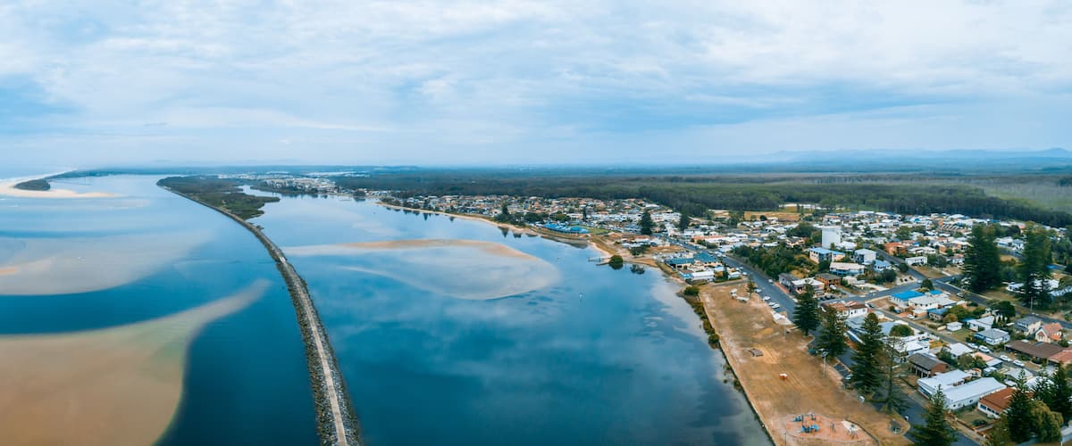 An aerial view of a coastal town with a beach, a pier, and a river.