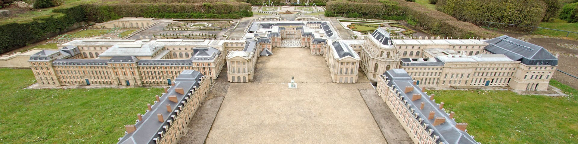 A large, symmetrical building complex with a central courtyard, surrounded by manicured gardens and pathways.