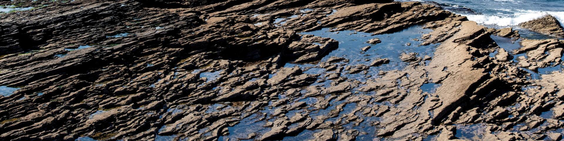 Panoramic view at Hook Head at the tip of Hook Peninsula, County Wexford, Ireland at the eastern entrance to Waterford Harbour with sloping Carboniferous limestone rocks into the ocean