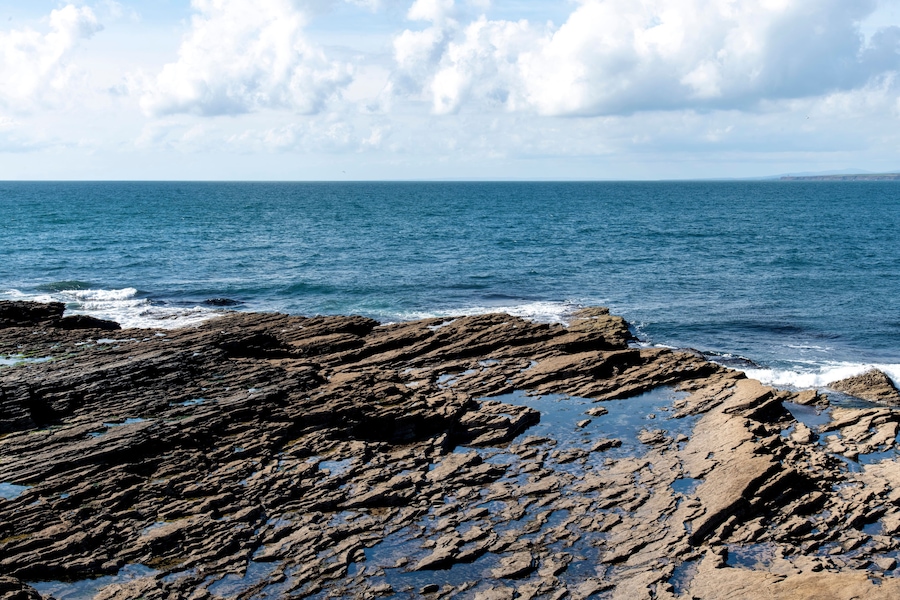 Panoramic view at Hook Head at the tip of Hook Peninsula, County Wexford, Ireland at the eastern entrance to Waterford Harbour with sloping Carboniferous limestone rocks into the ocean