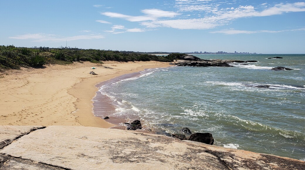 Isolated sun umbrella in north sea beach at Rio das Ostras, Rio de Janeiro, Brazil. Restinga and rocks.
