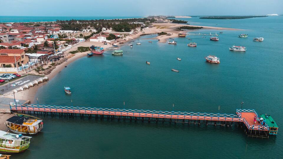 A coastal town with a pier, boats, and a sandy beach.
