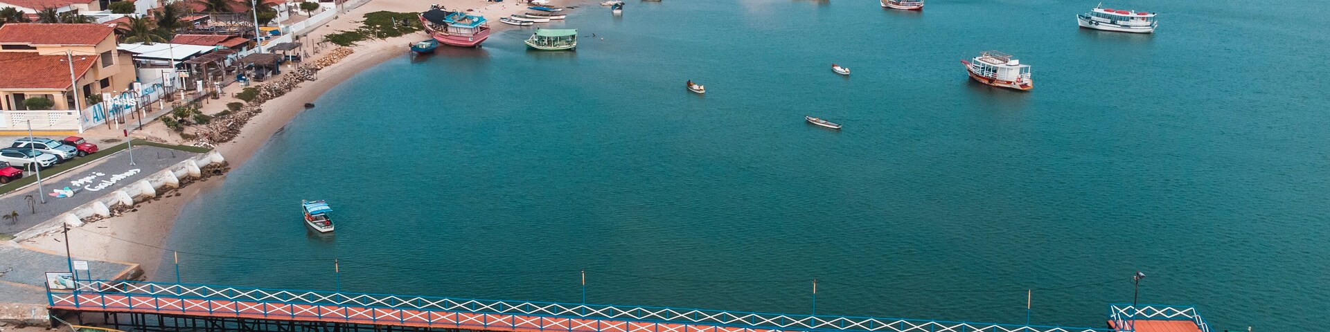 Un pueblo costero con muelle, barcos y una playa de arena.