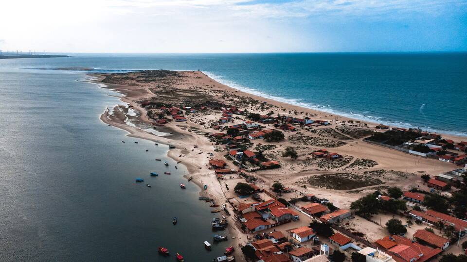 An aerial view of a coastal village with houses, boats, and a beach.