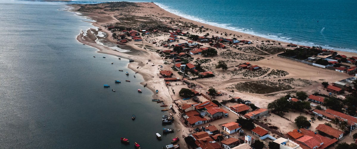 An aerial view of a coastal village with houses, boats, and a beach.