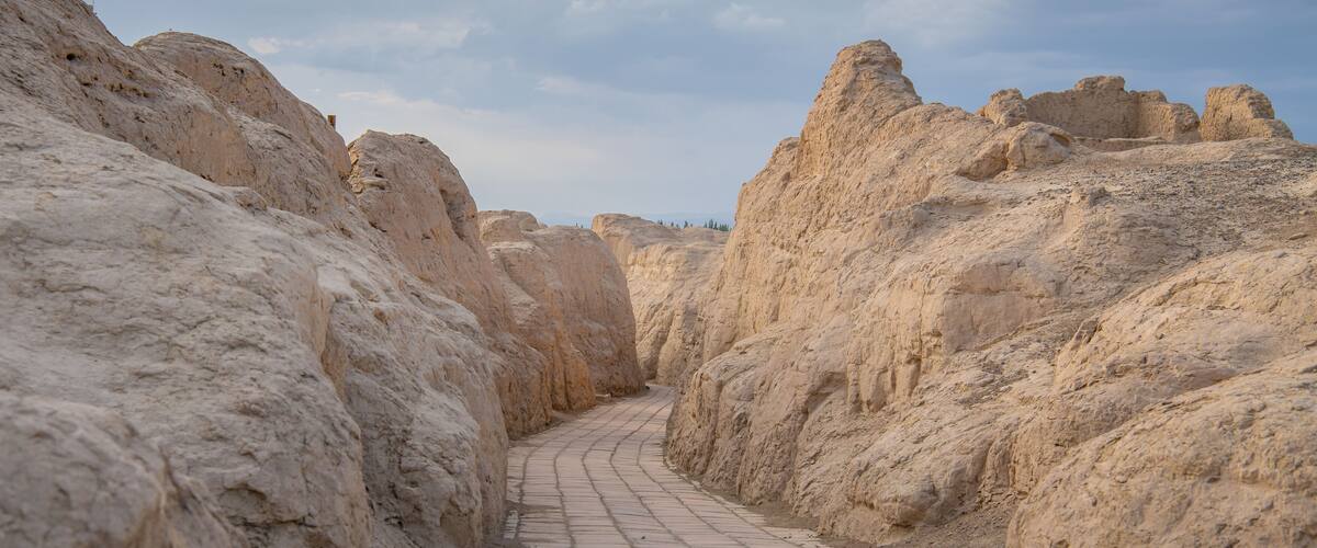 A narrow, rocky pathway flanked by towering, eroded sandstone cliffs.