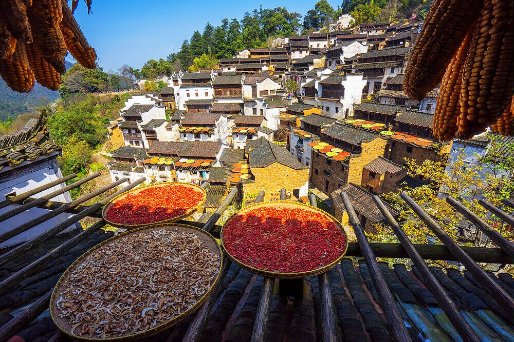 A traditional village with terraced houses, hanging corn, and dried chili peppers.