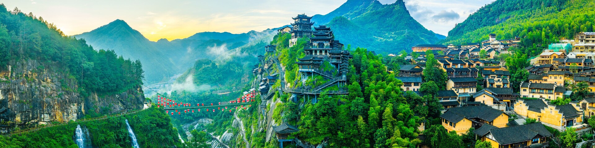 Beautiful ancient village with traditional wooden buildings on the green mountain at sunrise in Jiangxi, China.