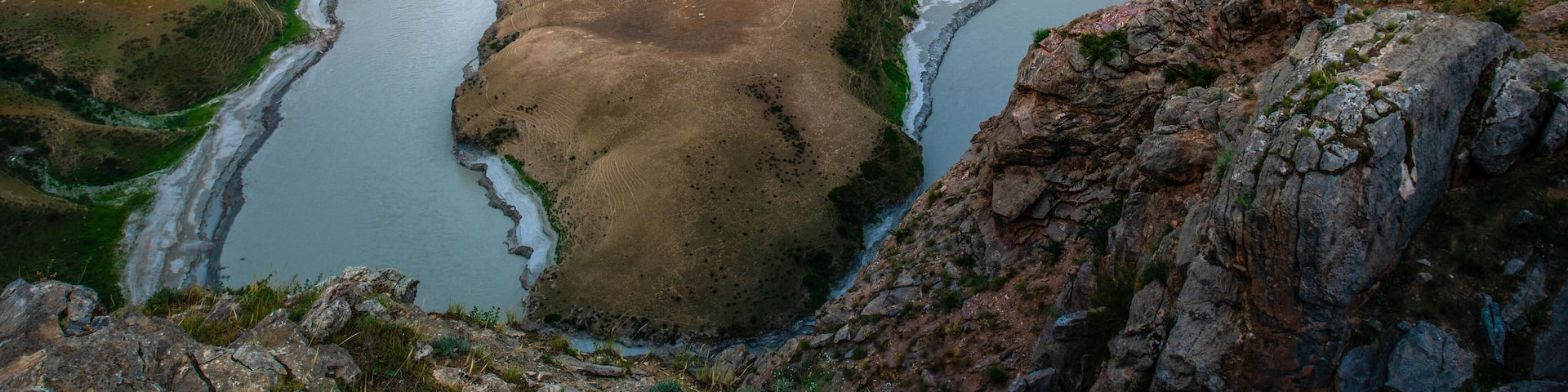 A river winding through a mountainous landscape with rocky terrain and sparse vegetation.
