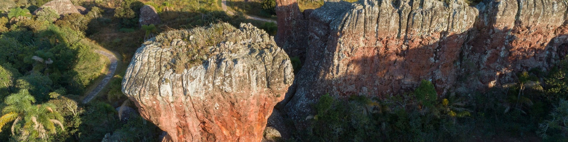 A landscape with prominent rock formations, a winding path, and a distant view of hills.