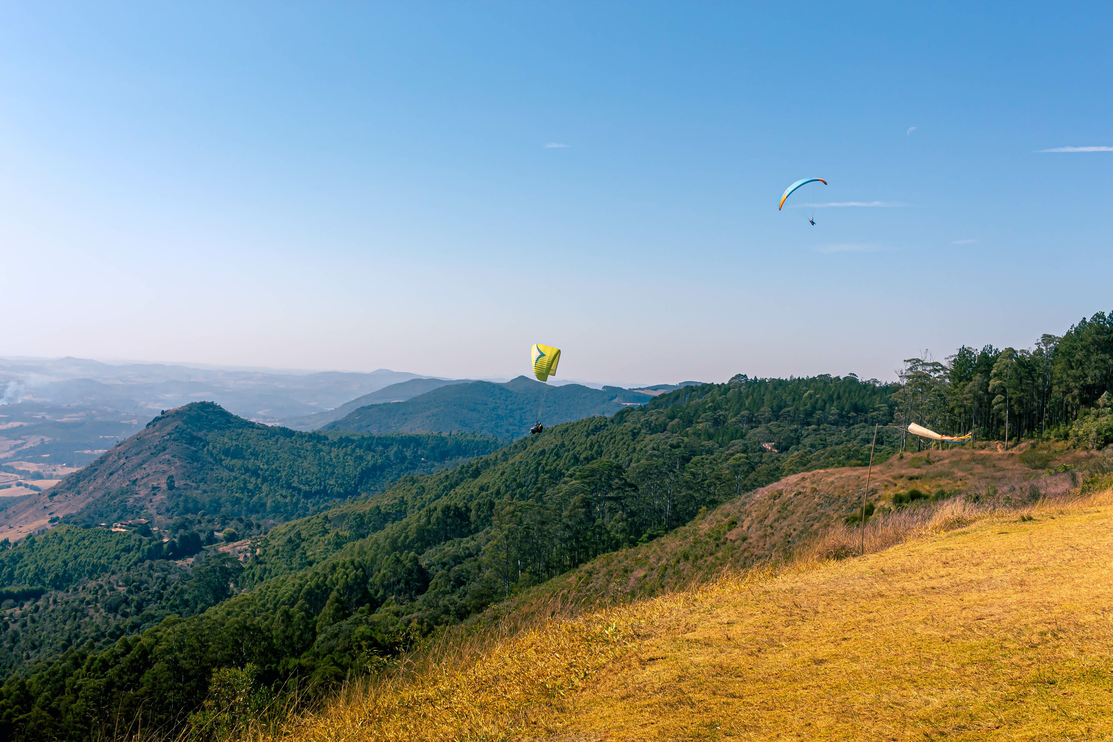 two paraglides flying over mountains in Poços de Calda Brazil.
