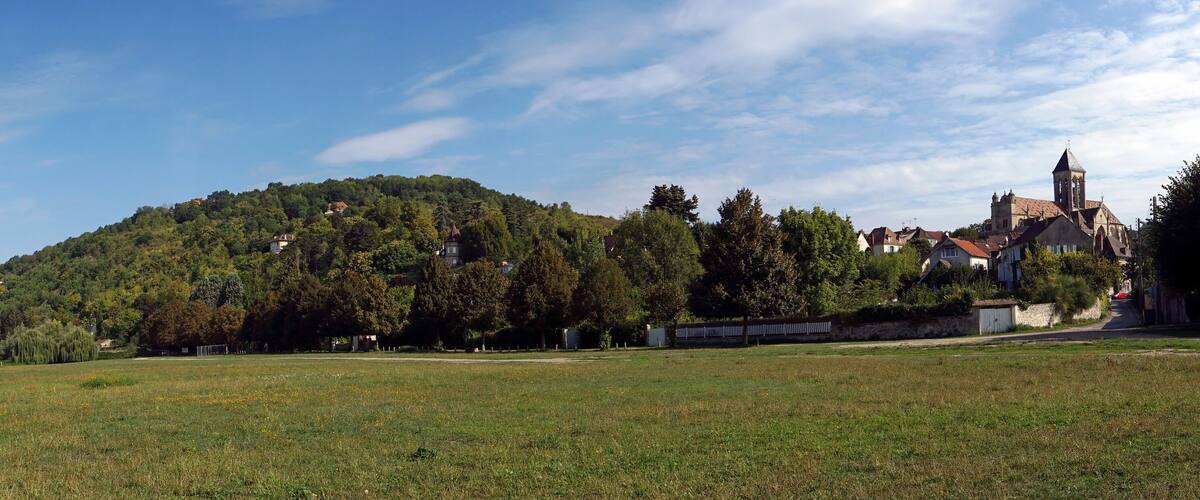 A grassy field, a hill with trees, and a church with a bell tower.