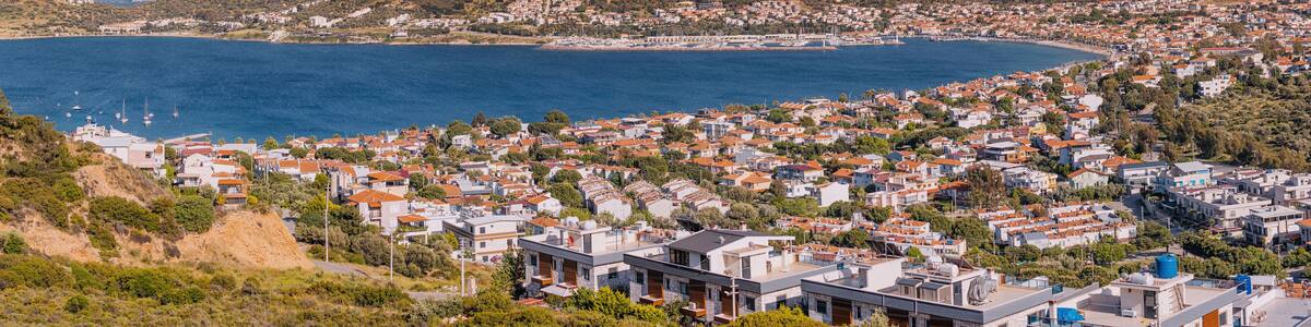 A coastal town with a bay, houses, and mountains in the background.