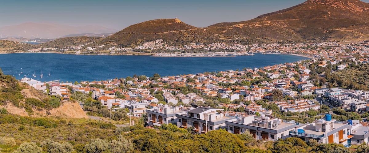 Un pueblo costero con una bahía, casas y montañas al fondo.