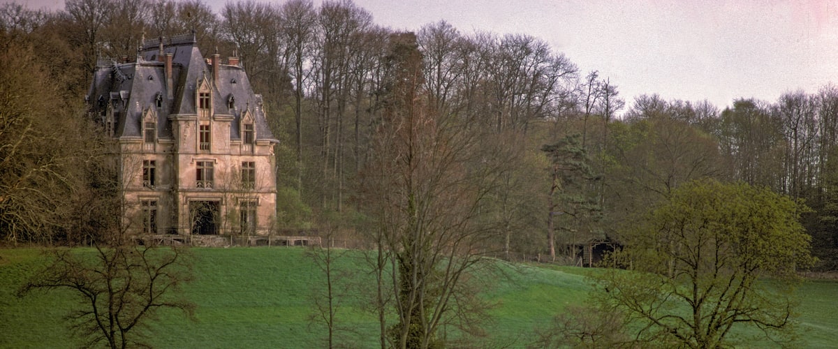 A large estate with a prominent building surrounded by a lush green field and trees.