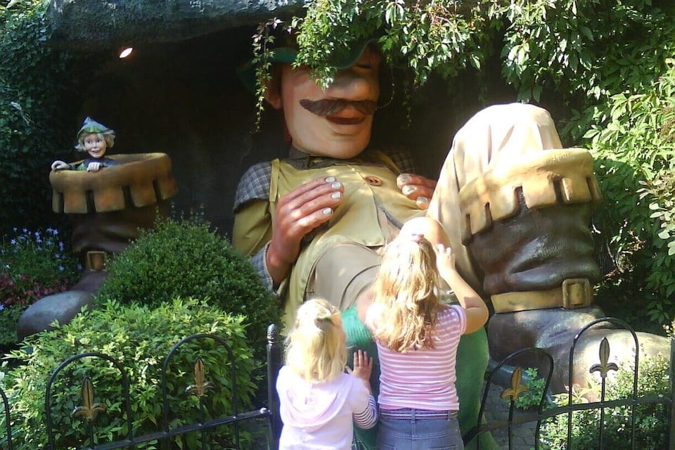 A large statue of a man with a mustache and a hat, surrounded by greenery and a fence.