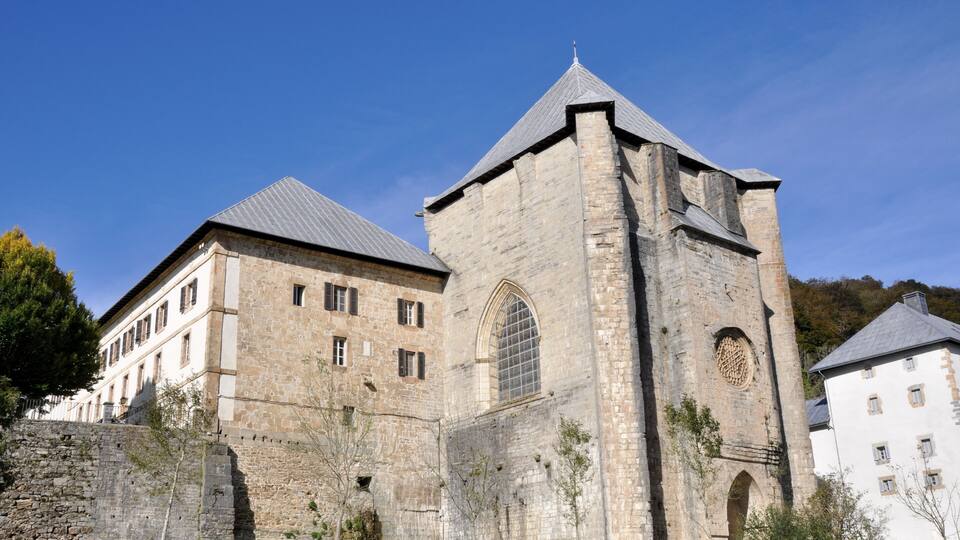 A historic stone building with a prominent tower and arched windows.