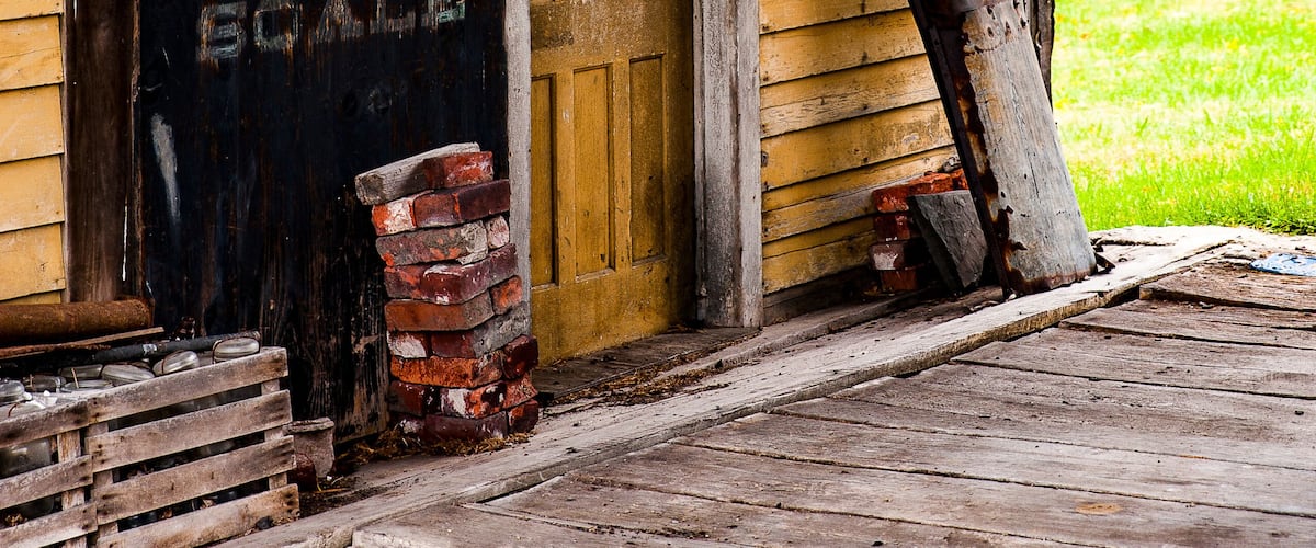 A rustic wooden building with a 'HOWE SCALE' sign, a window, and a brick structure beside it.