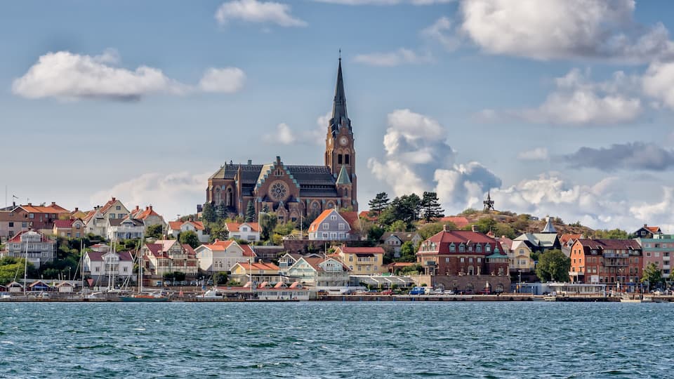 A coastal town with a prominent church featuring a tall spire and a clock tower.