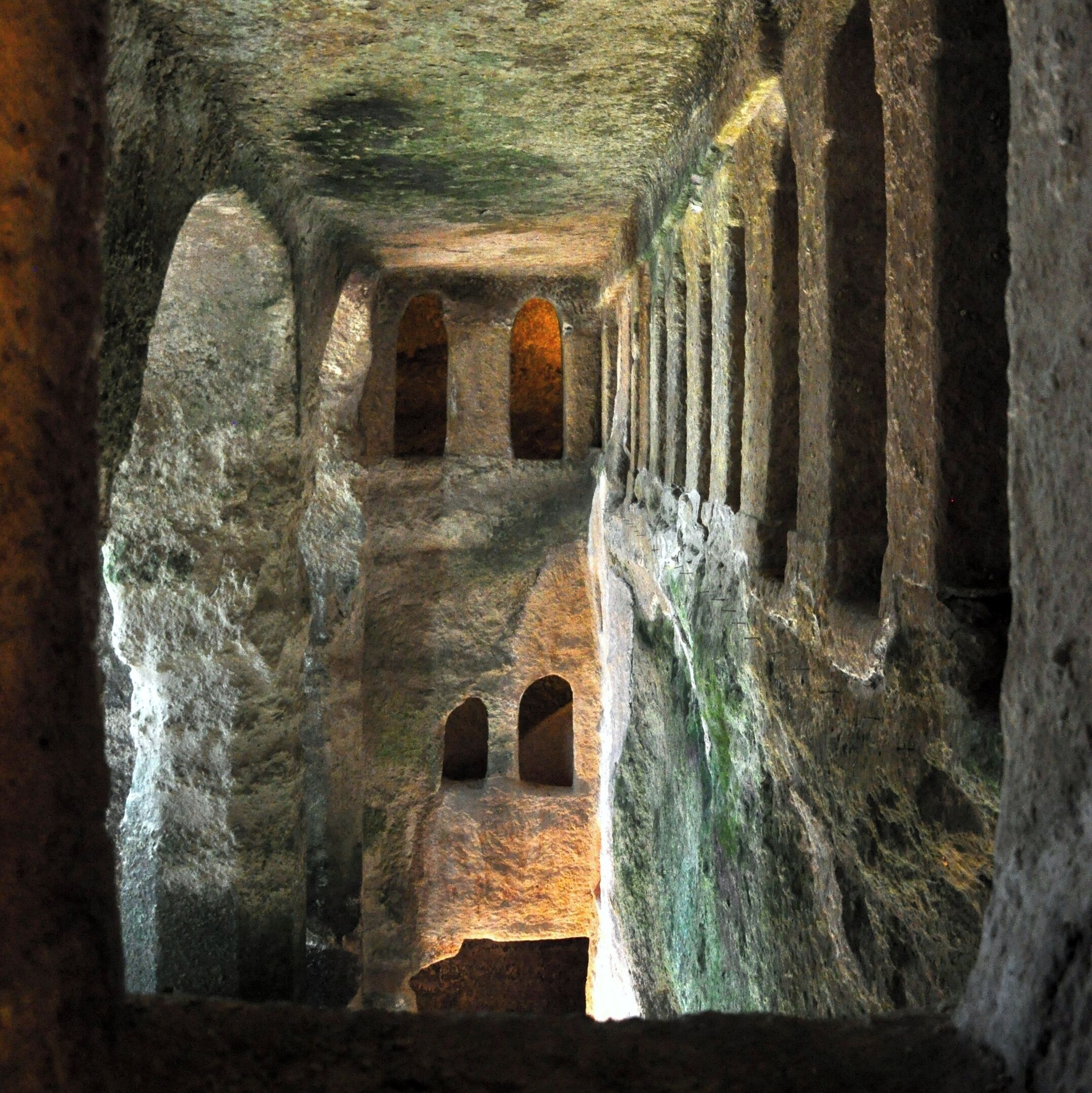 An ancient cave with arched passageways and rock formations.