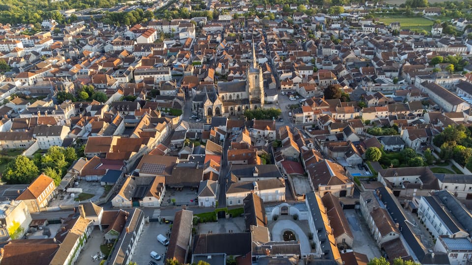 A densely packed town with historic buildings, a prominent church, and surrounding green fields.