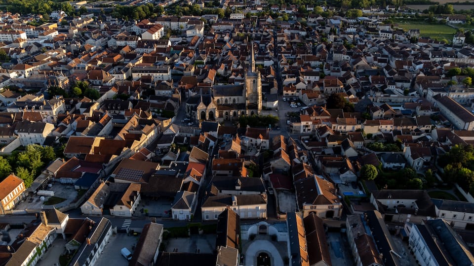 An aerial view of a densely packed town with historic buildings and a prominent church tower.