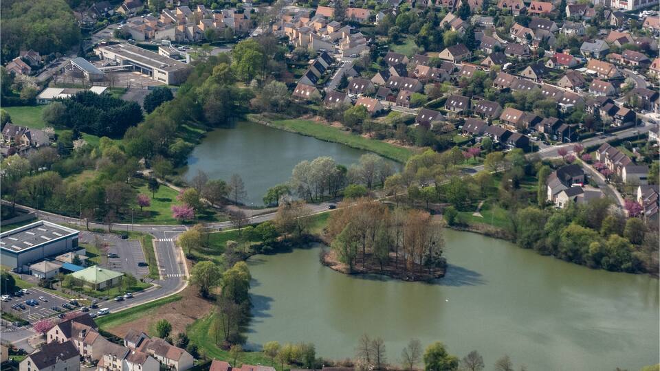 An aerial view of a residential area with a river, houses, and a large building complex.