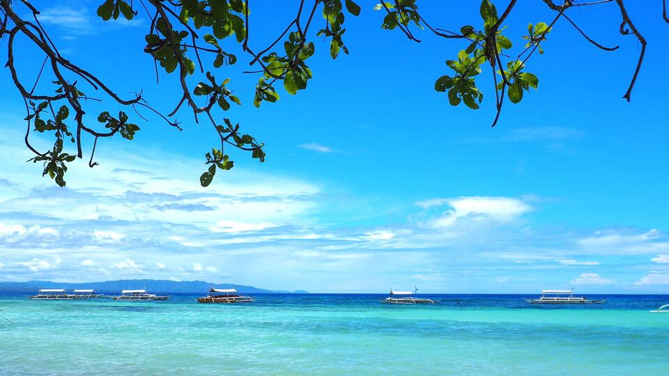 A clear blue sky, turquoise sea, and several boats.