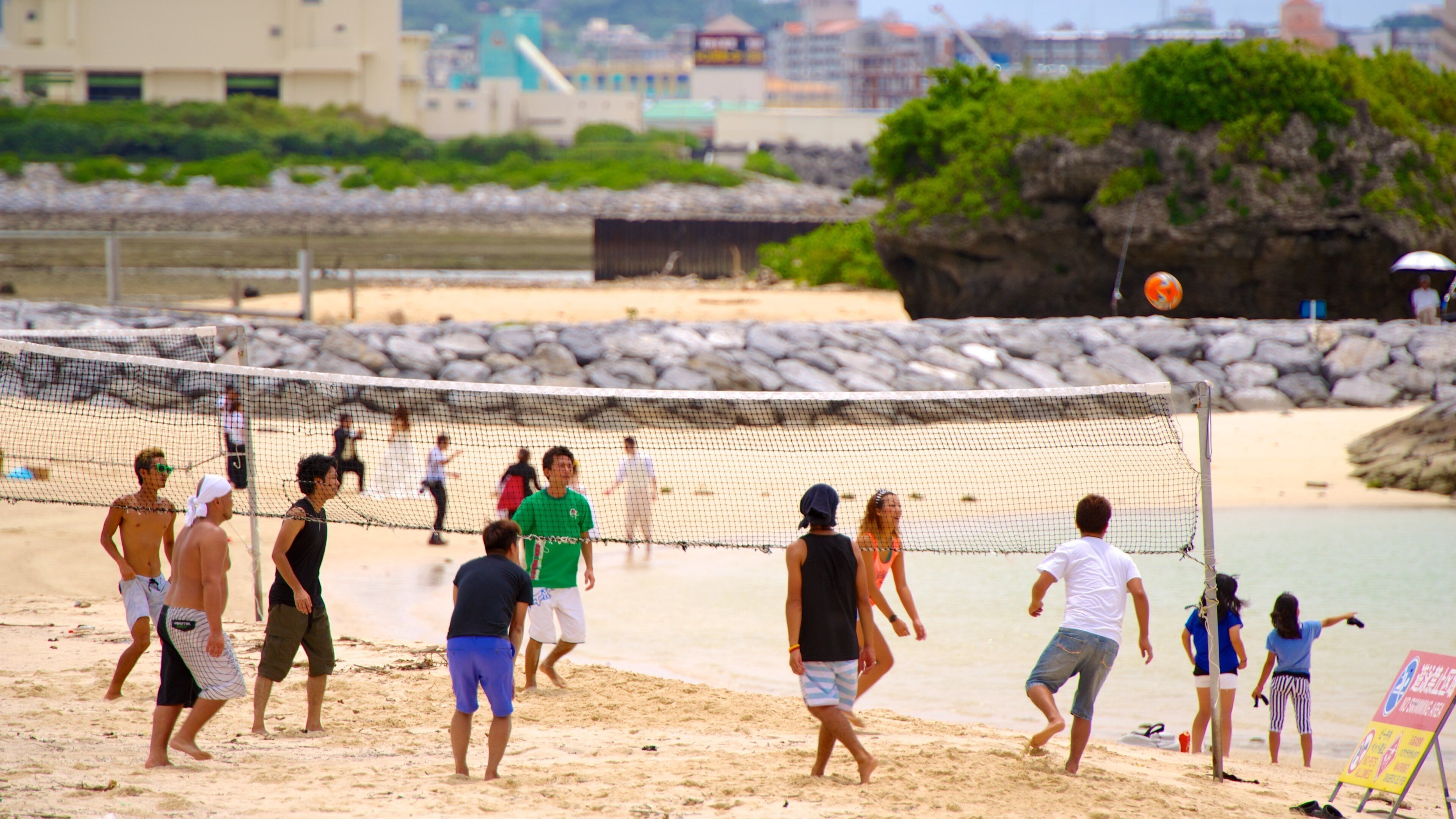 A beach volleyball game with players and spectators.