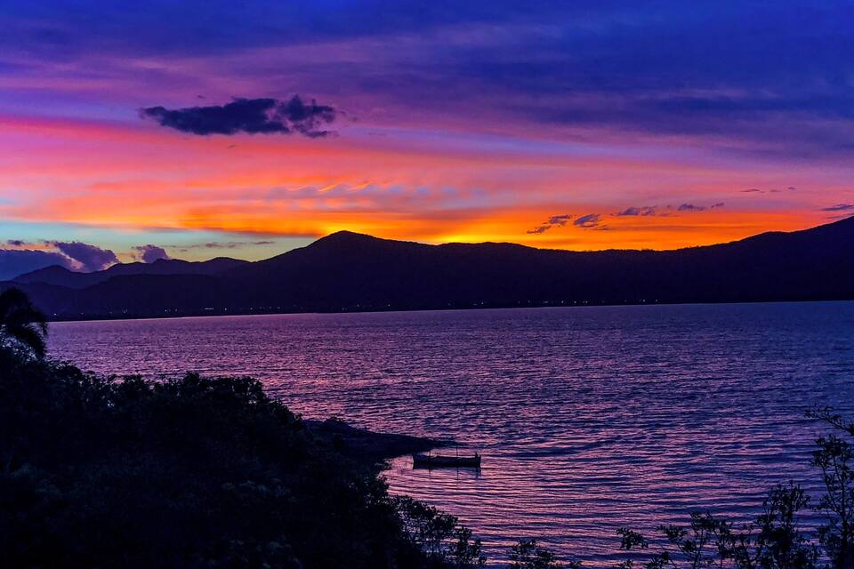 Una puesta de sol sobre un lago tranquilo con montañas al fondo.