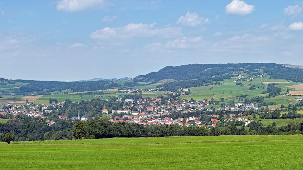 Une vallée verdoyante où se trouve une petite ville, nichée au milieu de collines douces et de forêts.