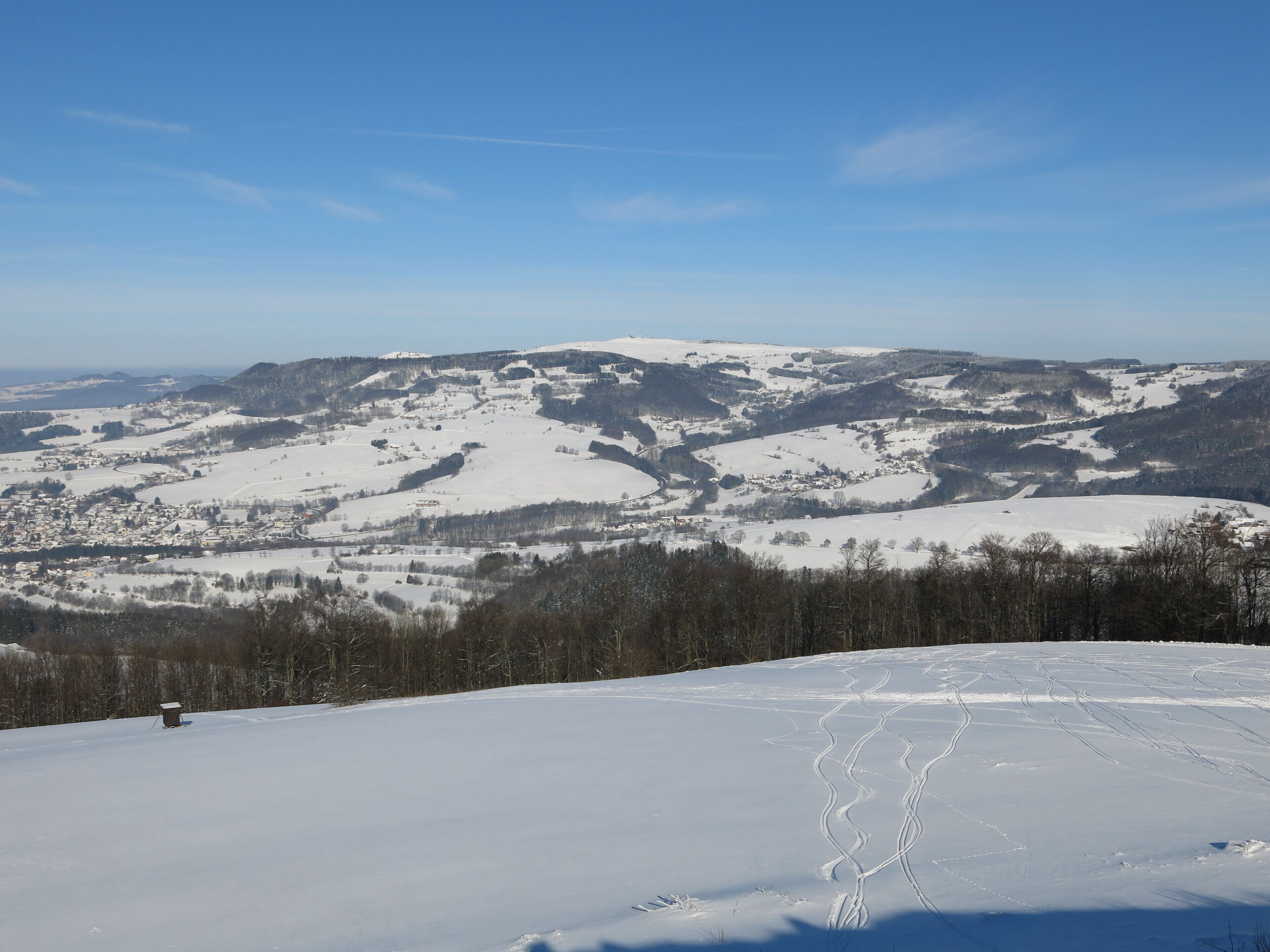 A snowy mountain landscape with ski trails and a small cabin.