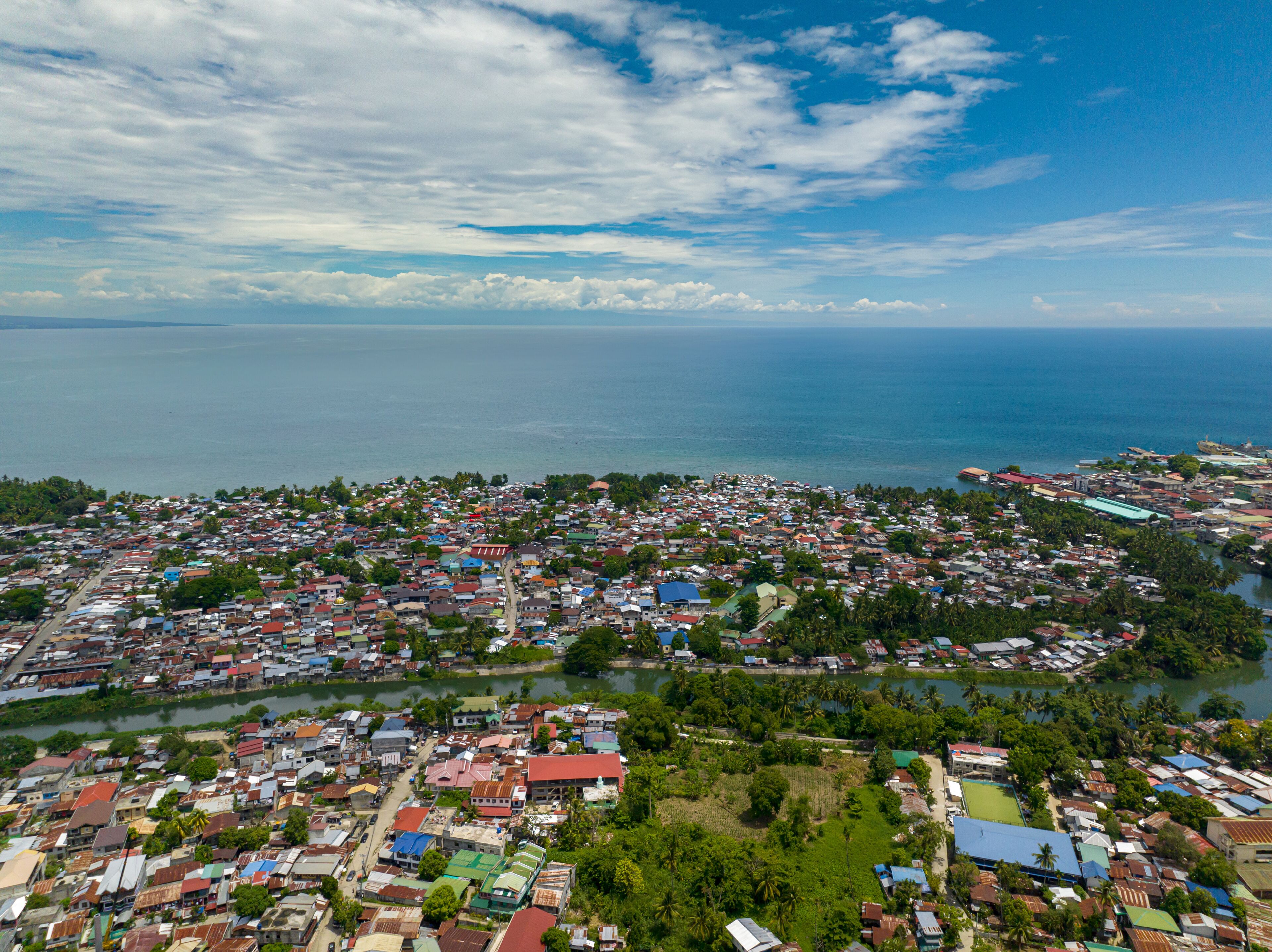 A coastal town with dense housing, a river, and a large body of water.