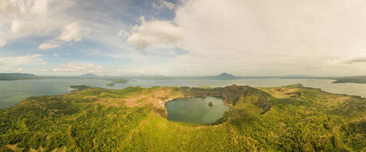 A volcanic crater surrounded by lush greenery and a large lake.