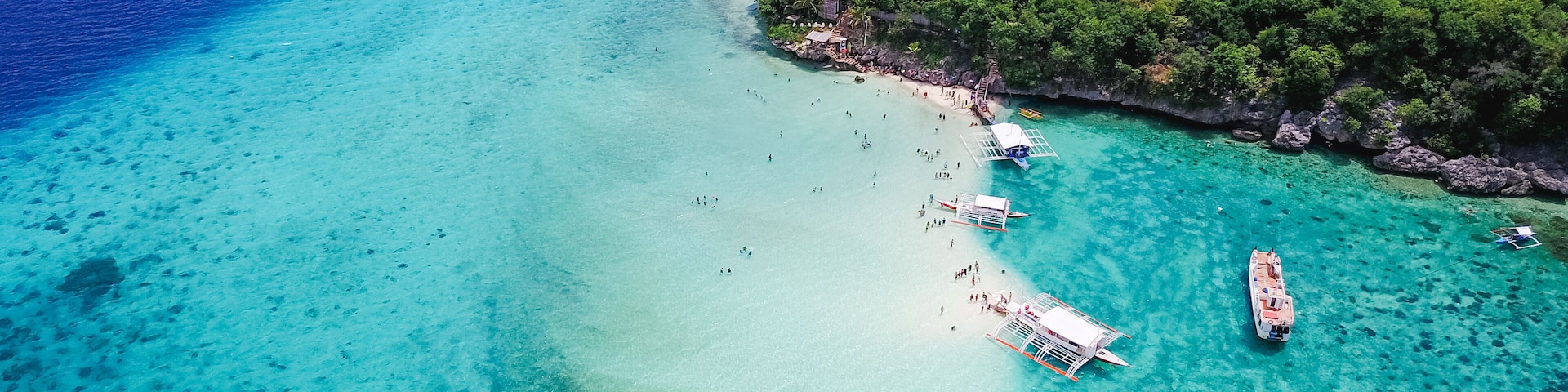 Aerial view of sandy beach with tourists swimming in beautiful clear sea water of the Sumilon island beach landing near Oslob, Cebu, Philippines