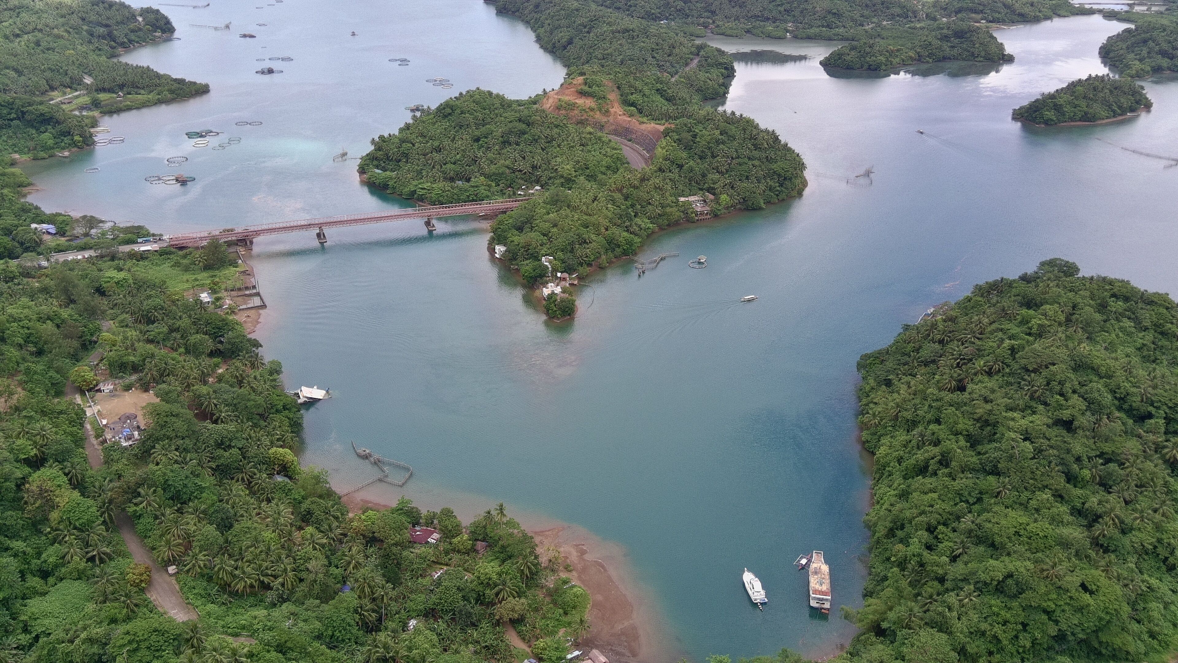 An aerial view of a river with several small islands, a bridge, and boats.