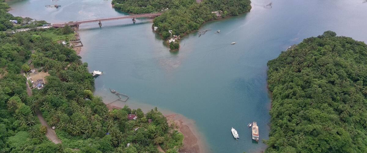 An aerial view of a river with several small islands, a bridge, and boats.