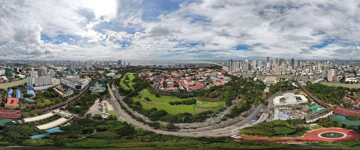 A panoramic view of a city with a river, green spaces, and a mix of modern and traditional architecture.