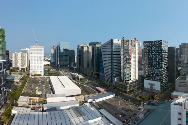 Paisagem urbana com arranha-céus modernos, um edifício branco grande com um padrão único e um hospital com heliponto.
