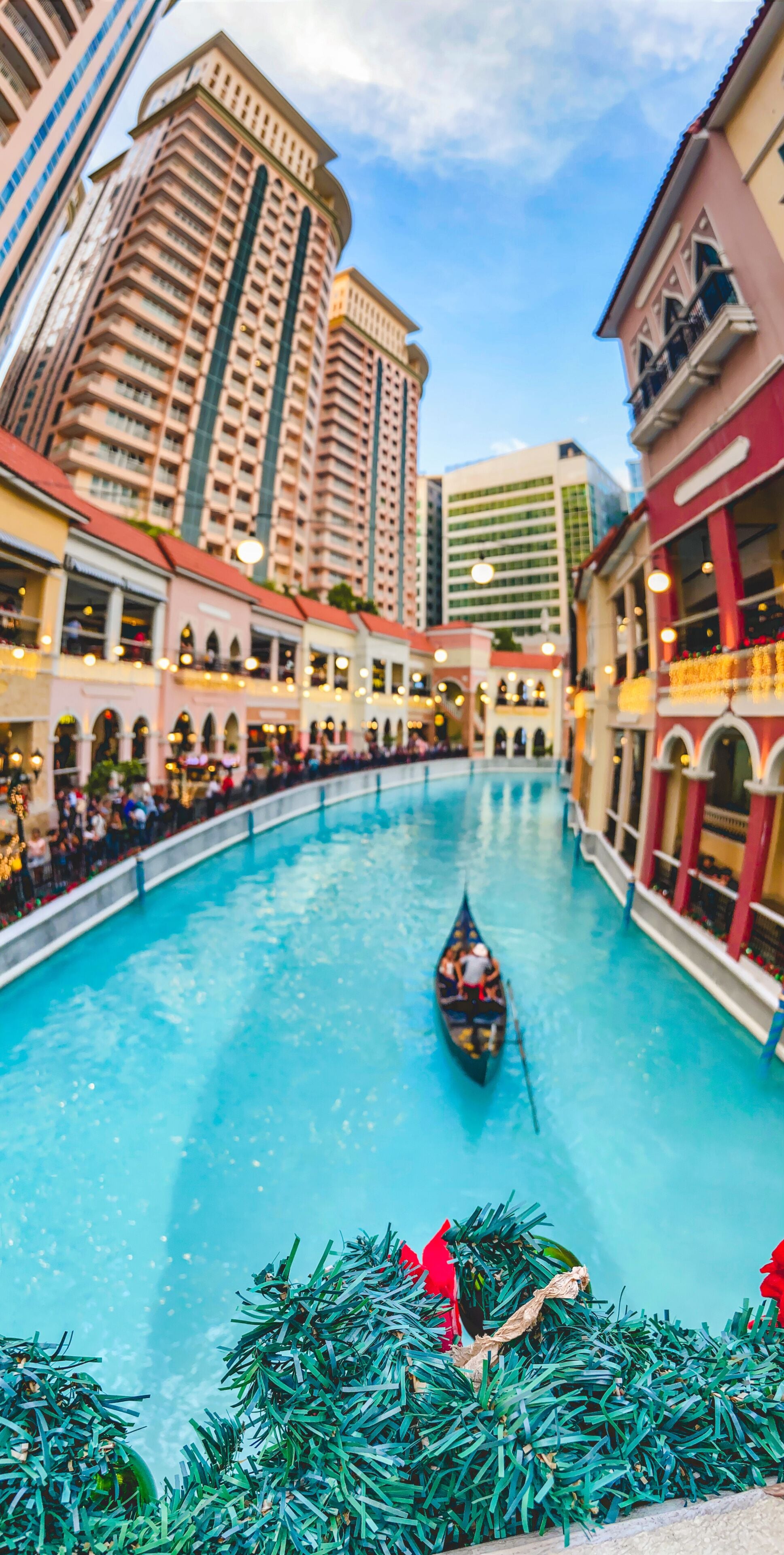 A gondola on a canal in a city with tall buildings and a clear sky.