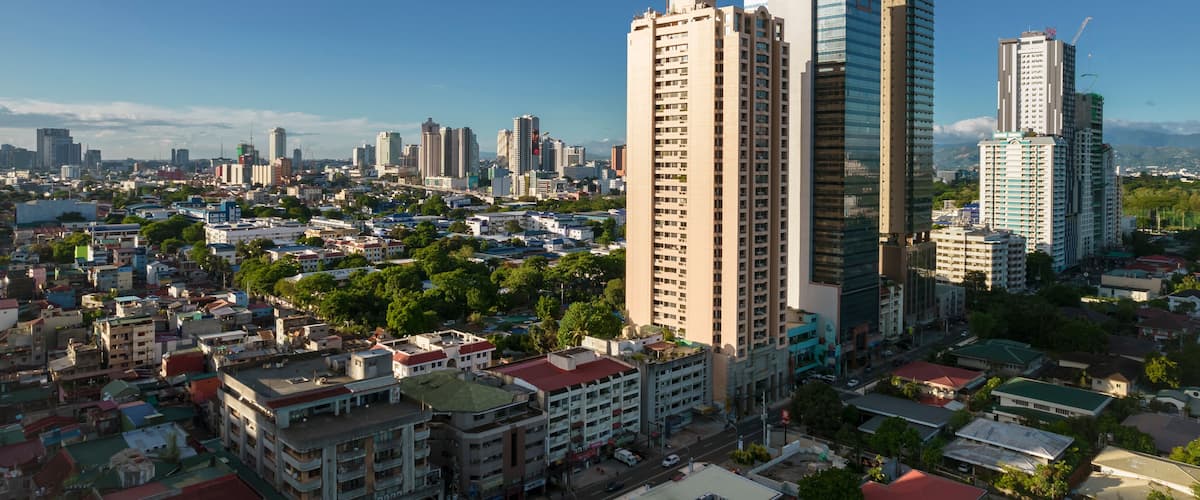 A cityscape with tall buildings, including a prominent skyscraper with a spire, surrounded by smaller residential and commercial structures.
