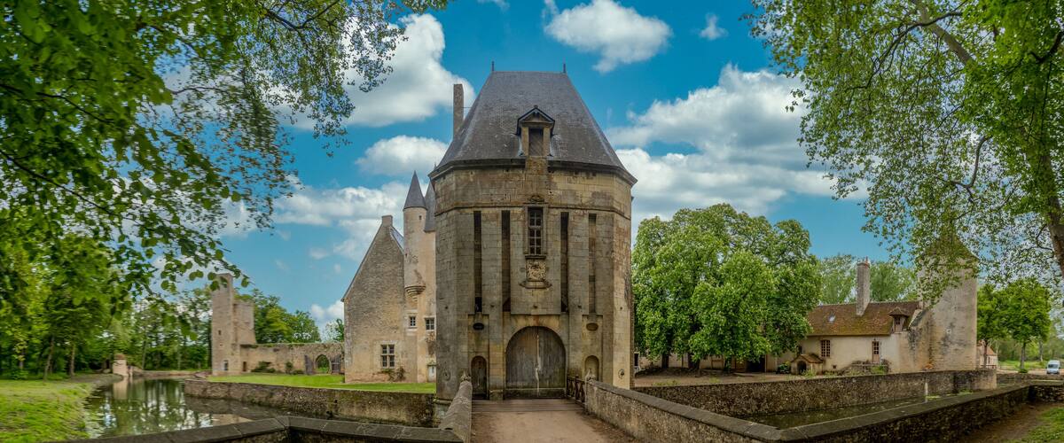 A historic stone building with a central tower and a moat.