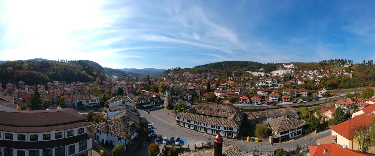 A town with red-roofed buildings, a prominent church, and surrounding hills.