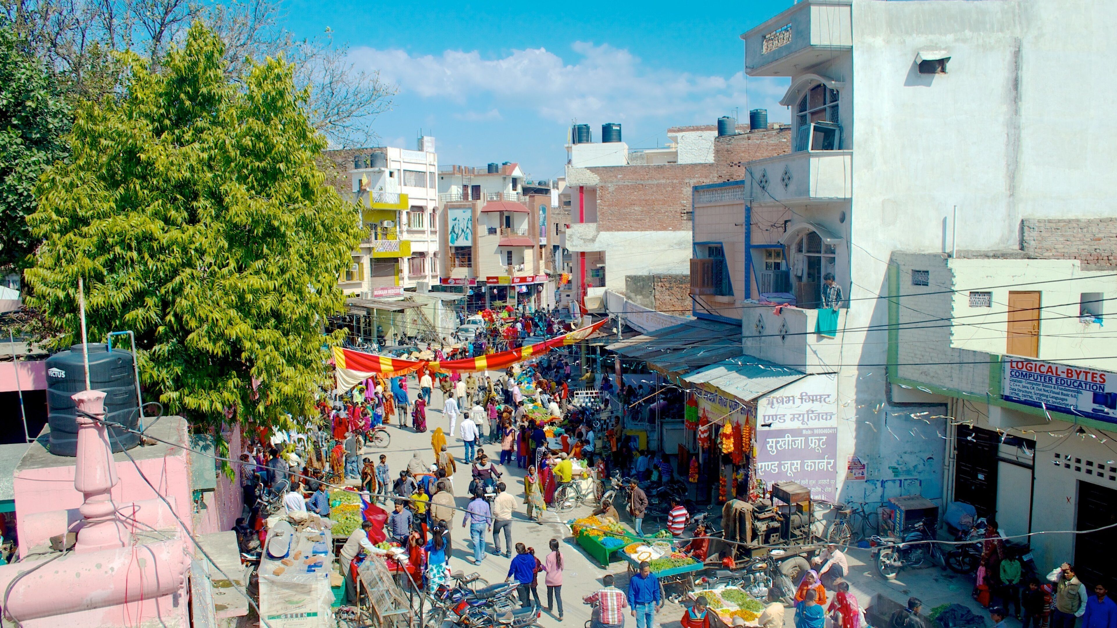 A bustling street market with people shopping and vendors selling goods.