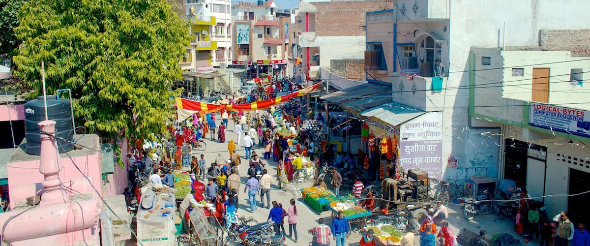 A bustling street market with people shopping and vendors selling goods.