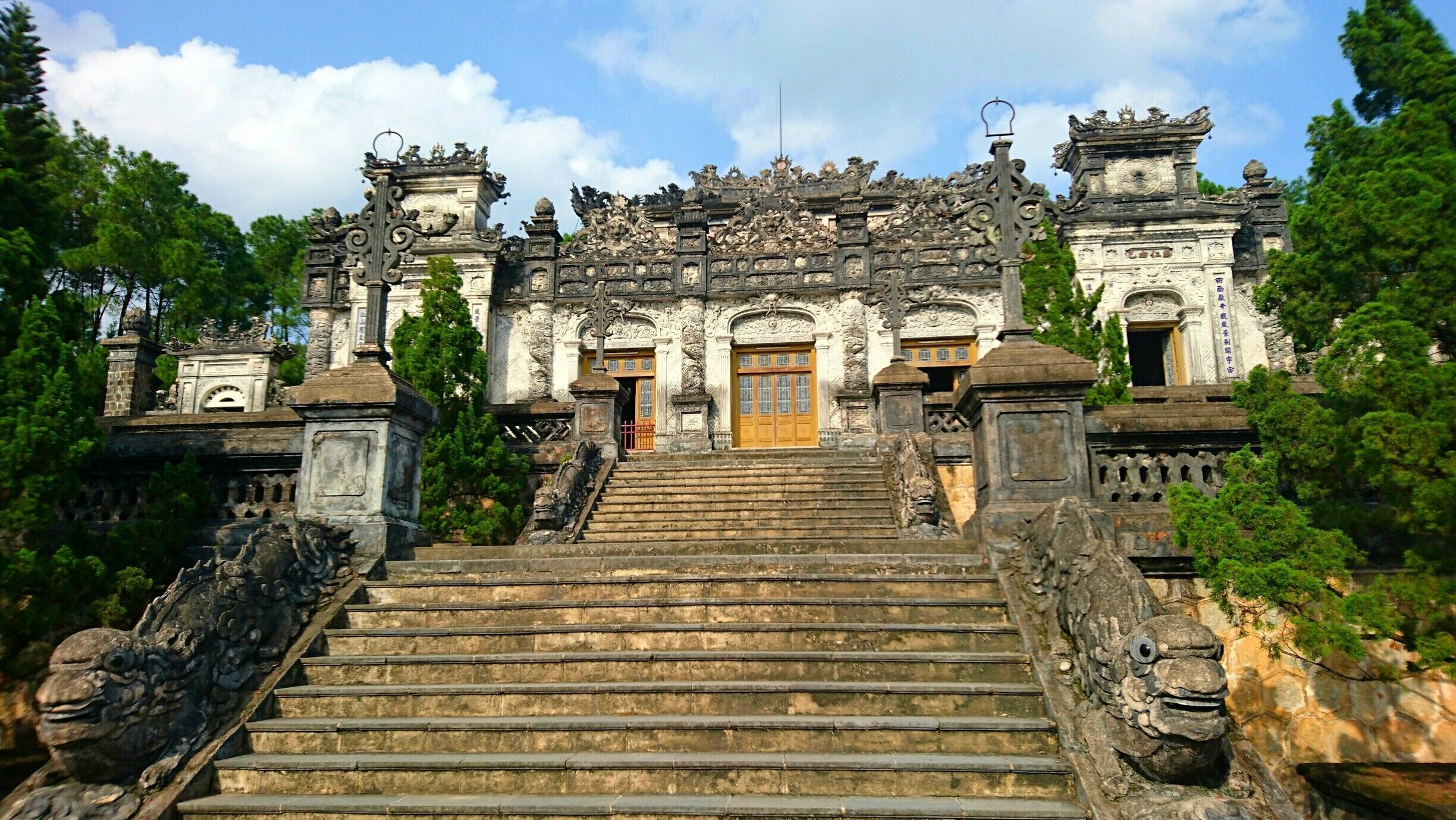 A grand temple with ornate carvings, a large central doorway, and a staircase leading up to it.